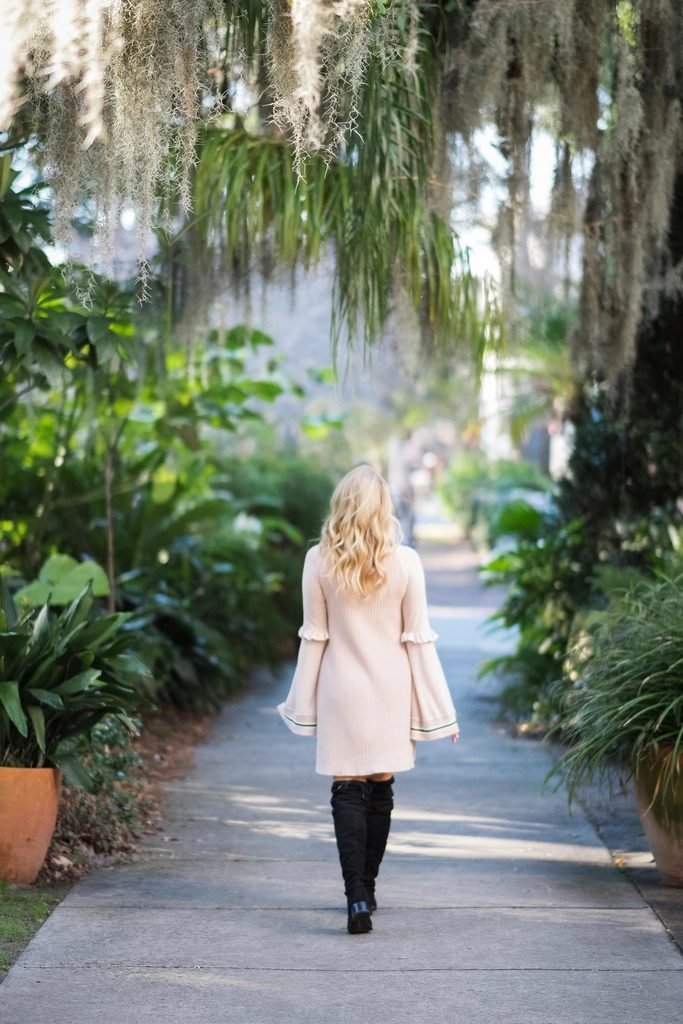 A person walking forward along a calm tree-lined path