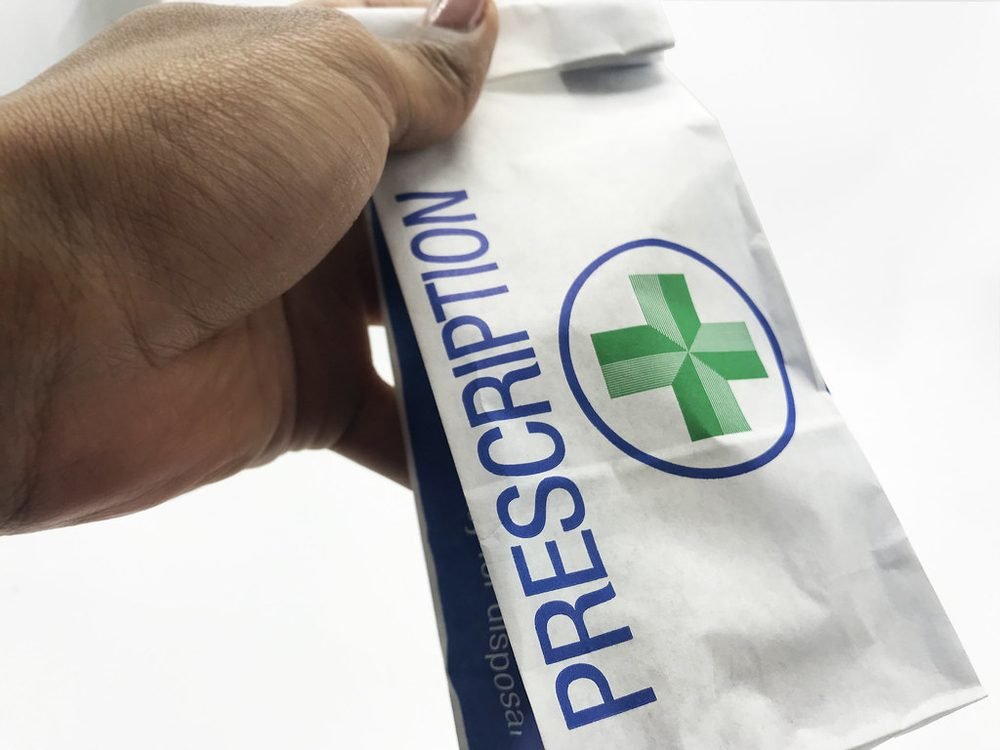 A hand holding a prescription bag from a pharmacy